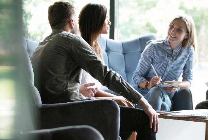 Picture with three employees on a sofa at AirPlus, depicts the working environment and team culture.