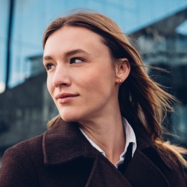In front of an office building, a woman gazes resolutely into the distance.